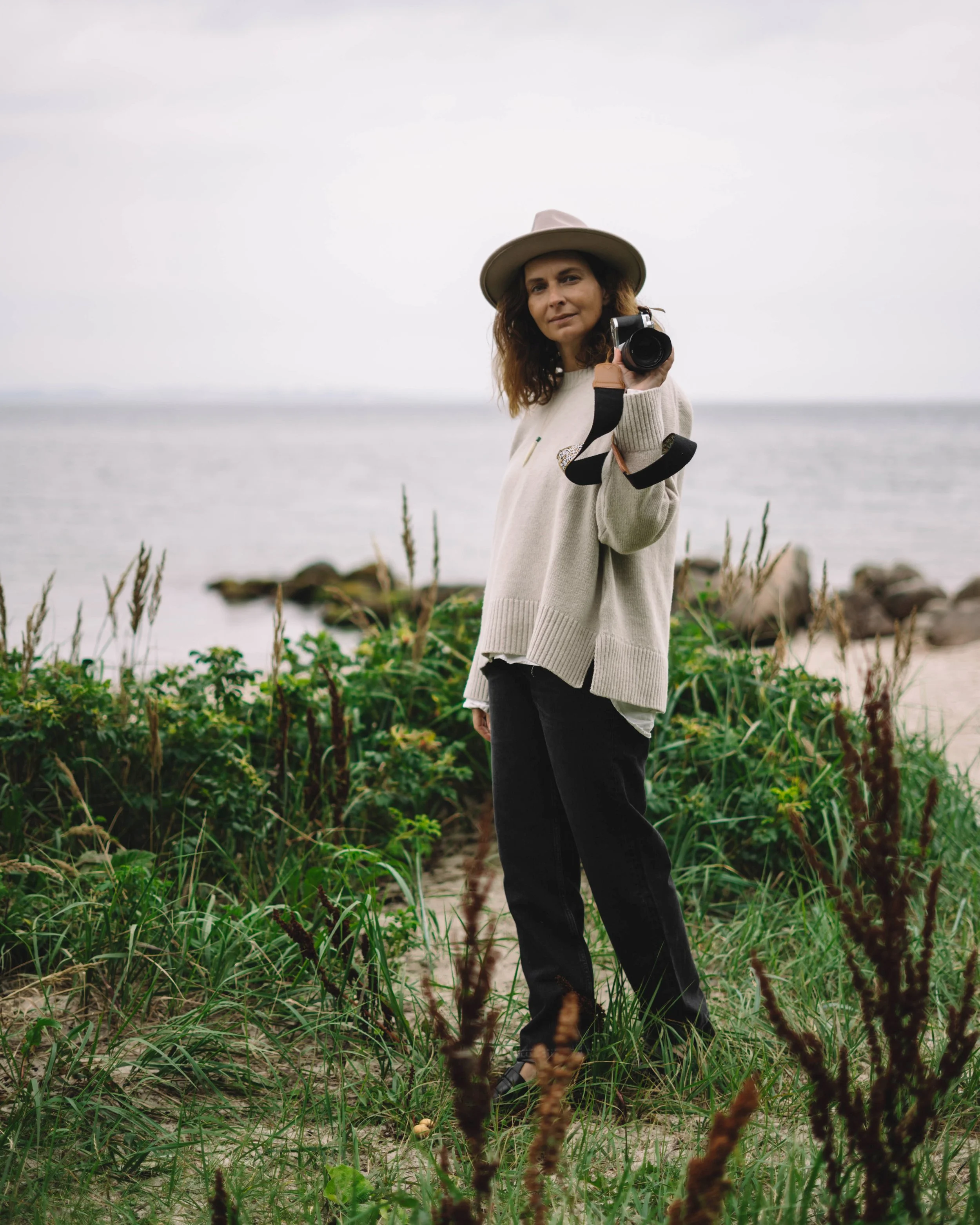 Michèle Gabrielle holding a camera by the sea